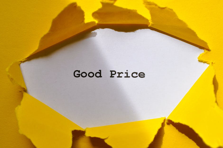 A white rectangular card with the words 'Good Price' printed in black font is visible through a torn yellow paper background. The torn paper has jagged edges, revealing the card beneath. The scene appears to be set on a flat surface with the torn paper flaring outward, suggesting a deliberate tearing. The lighting is even, highlighting the contrast between the bright yellow paper and the white card. The image relates to cost transparency in house removals and packing services, with subtle reference to clear, upfront pricing provided by Man with Van Seven Kings for home relocation or furniture transport tasks.